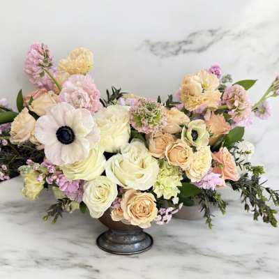 Pastel floral arrangement in a low pedestal vase with roses and anemones