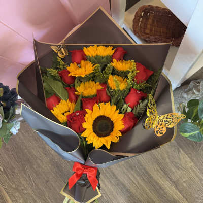 Bouquet of red roses and yellow sunflowers wrapped in dark paper
