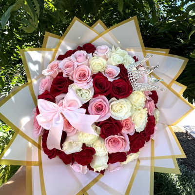 Round bouquet of red, pink, and white roses with a pink bow and crown pick