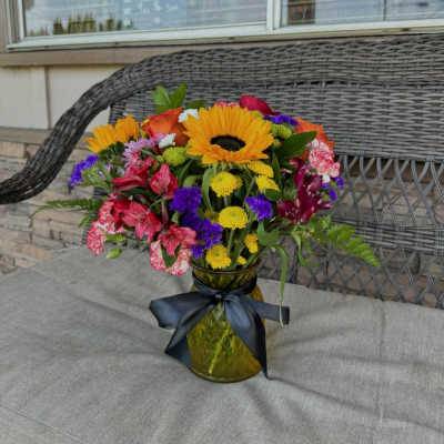 Colorful mixed bouquet in a glass vase with a dark ribbon