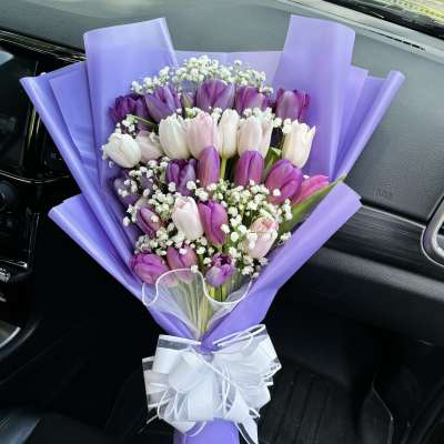 Bouquet of purple, pink, and white tulips wrapped in lavender paper