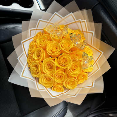 Bouquet of yellow roses wrapped in translucent paper with butterfly accents