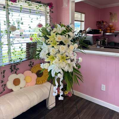 Tall white floral standing spray with lilies and roses on an easel