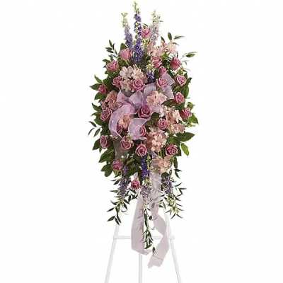 Tall standing floral spray with pink roses and lavender ribbon on an easel