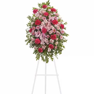 Standing floral spray of pink and red flowers on a white easel