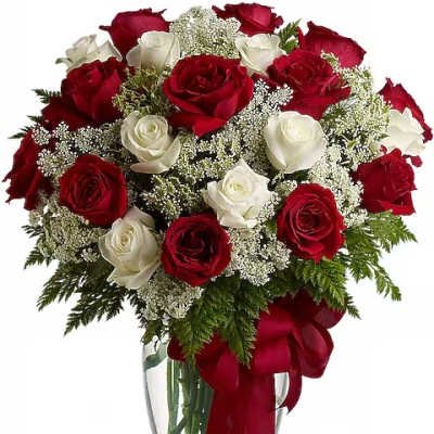 Red and white roses in a clear glass vase with a red ribbon