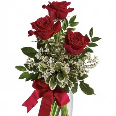 Red roses in a clear glass vase with a red ribbon