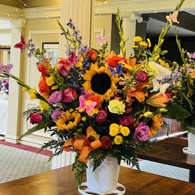 Large mixed flower arrangement with sunflowers and roses in a white vase