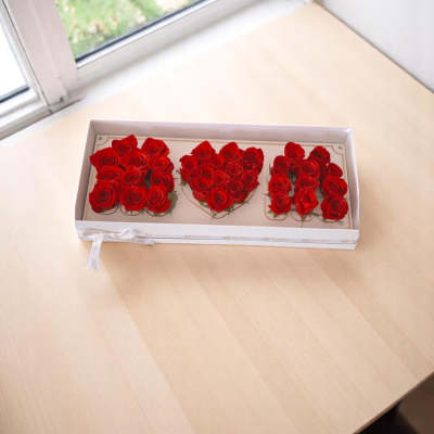 Boxed arrangement of red roses arranged as three letters