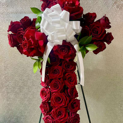 Cross-shaped arrangement of red roses with a white bow