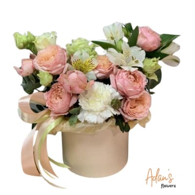 Pink and white flower arrangement in a round beige box with ribbon