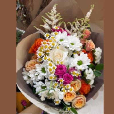 Mixed bouquet of roses and daisies wrapped in brown paper