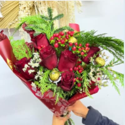 Bouquet of red roses with berries and greenery in red wrap
