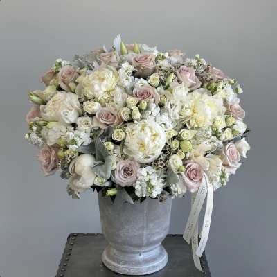 Blush and white rose bouquet in a gray pedestal vase