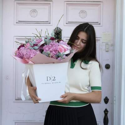 Woman holding a large pink flower bouquet in a white box