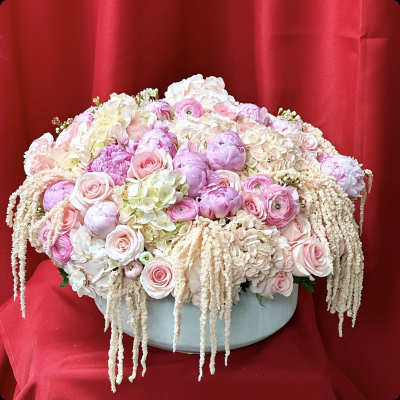 Large pastel pink and white floral arrangement in a round box