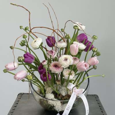 Mixed tulips and ranunculus in a clear glass bowl with a ribbon