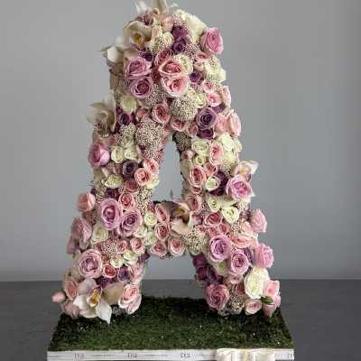Large floral letter A covered in pink and white roses and orchids