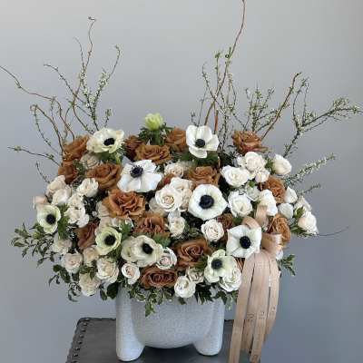 Large bouquet of white and brown roses with white anemones in a gray vase
