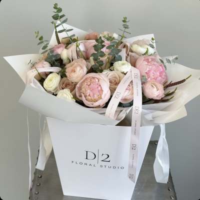 Blush pink and white bouquet with ribbon in a white gift bag