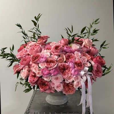 Large pink rose arrangement in a gray vase with ribbon tails