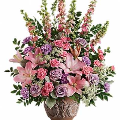 Tall pink and lavender flower arrangement with lilies and roses in an ornate brown vase
