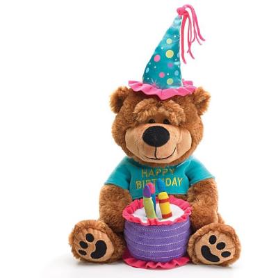 Plush brown birthday bear in a party hat holding a fabric cake with candles.