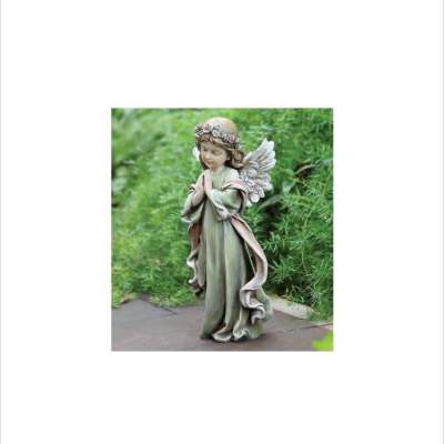 Garden angel statue of a praying child with wings and a flower crown on a stone path