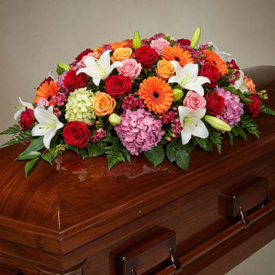 Colorful floral casket spray with roses, lilies, gerbera daisies, and hydrangeas