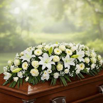 White floral casket spray with lilies, roses, and daisies