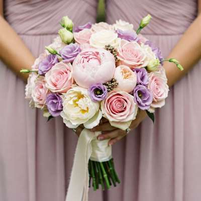 Handheld bouquet of pink, white, and lavender flowers with a ribbon wrap