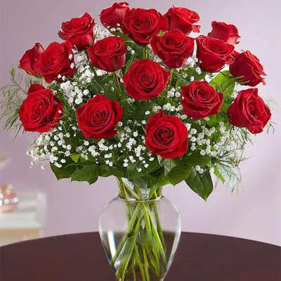 Red roses arranged in a clear glass vase with white filler flowers