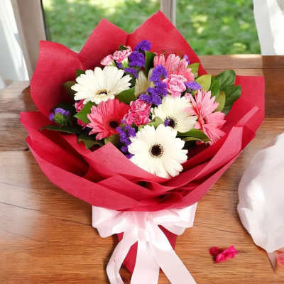 Bouquet of pink and white daisies with purple filler wrapped in red paper
