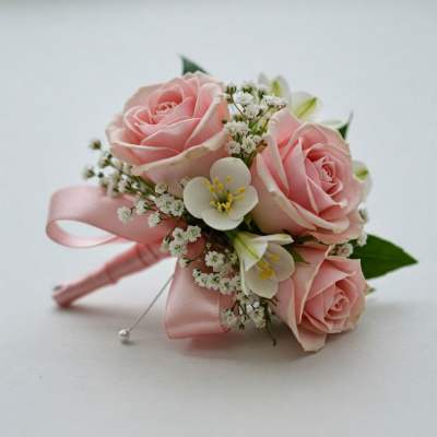 Pink rose boutonniere with white accent flowers and satin ribbon