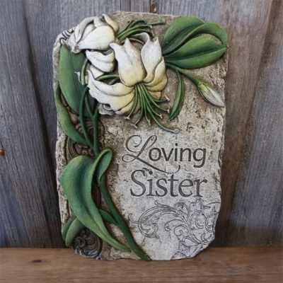 Stone memorial plaque with sculpted white flowers and the engraved words Loving Sister