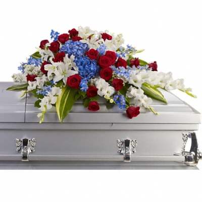 Red, white, and blue casket spray with roses, lilies, and hydrangeas on a silver casket.