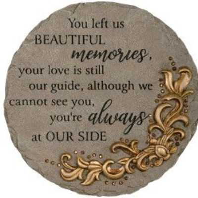 Round gray memorial stone with engraved sentiment and gold scroll design on one side