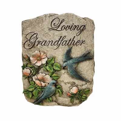 Memorial stone reading Loving Grandfather with blue birds and pink flowers in relief.