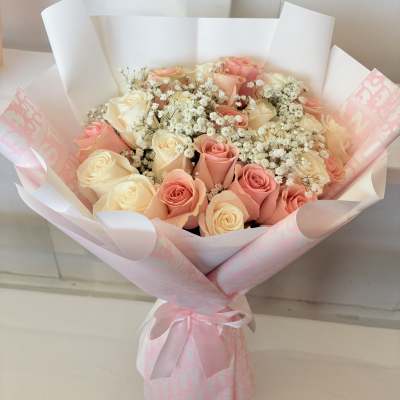 Bouquet of pink and cream roses with baby's breath in pink wrapping