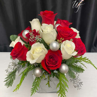 Red and white roses arranged in a square vase with silver ornaments