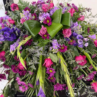 Large bouquet of pink and purple flowers with broad green leaves