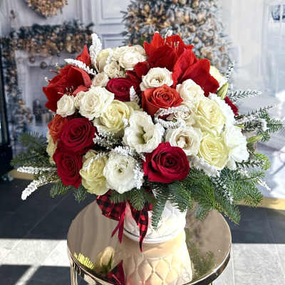 Bouquet of red and white roses in a white vase with evergreen accents