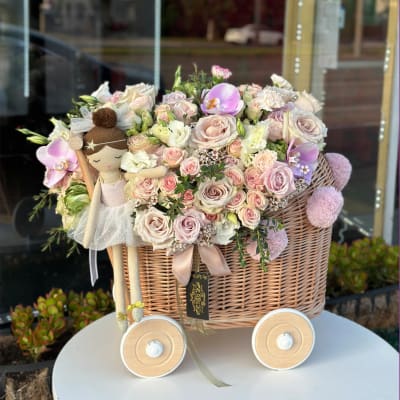 Pastel rose bouquet in a wicker basket with a doll decoration
