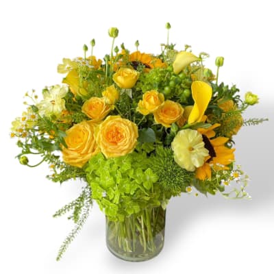 Yellow roses and mixed blooms arranged in a glass vase