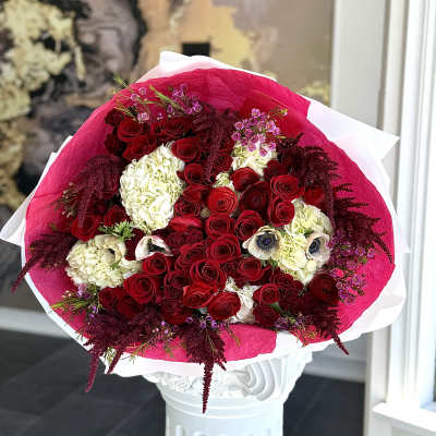Bouquet of red roses and white hydrangeas wrapped in pink paper