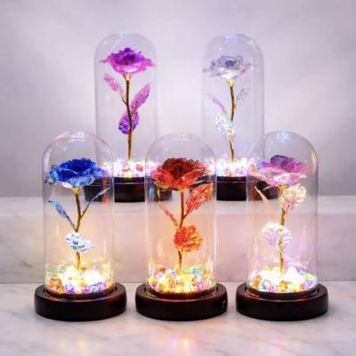 Four illuminated glass domes with colorful artificial roses on black bases