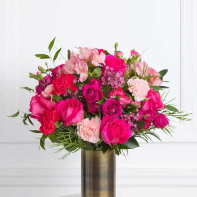 Pink and red flower arrangement in a tall gold vase