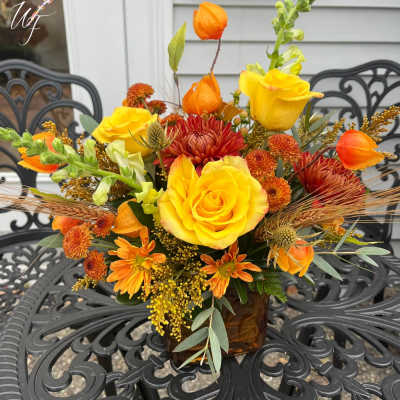 Yellow and orange flower arrangement in a brown glass vase