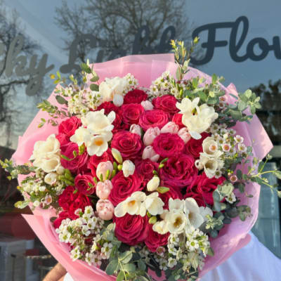 Large bouquet of pink and white roses wrapped in pink paper