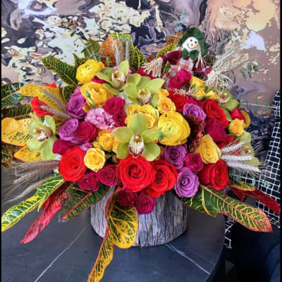 Colorful bouquet of roses and orchids in a wood container with a scarecrow pick